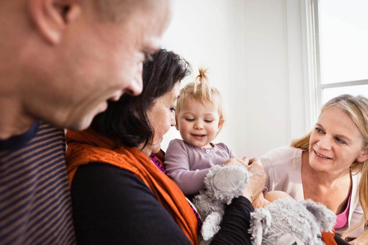 Eine Großmutter spielt mit ihrer Enkeltochter und zeigt ihr die Kuscheltiere.