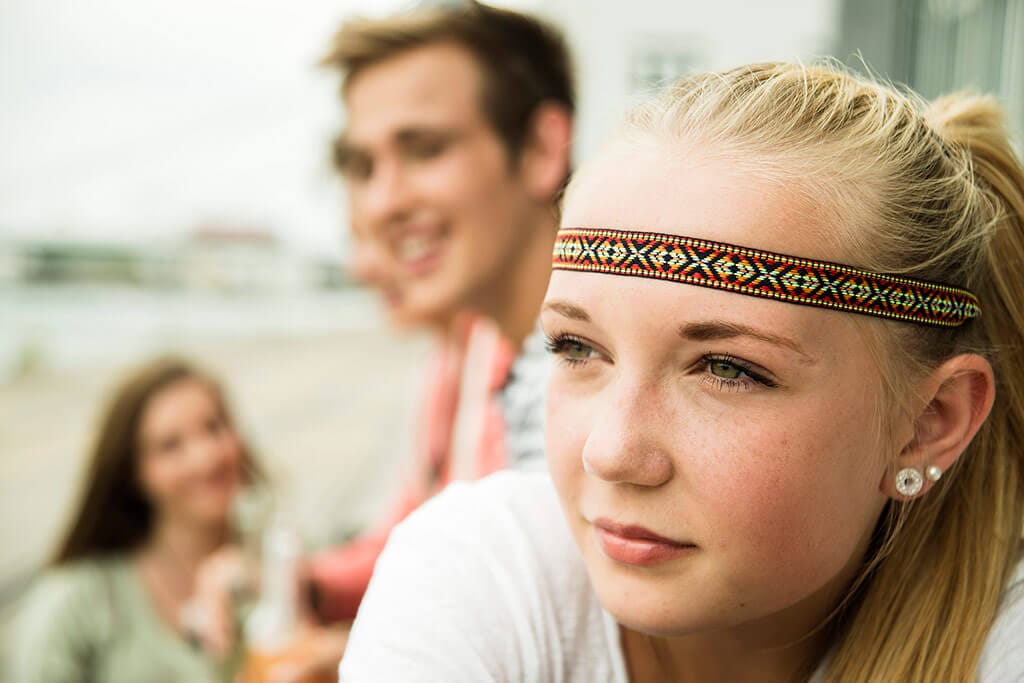 Ein junges Mädchen mit blonden Haaren schaut nachdenklich.