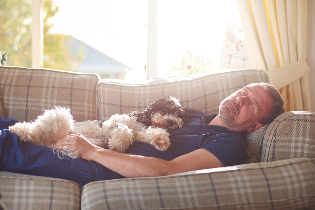 Mann mit Hund auf dem Sofa