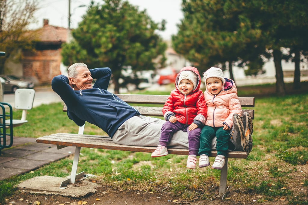 Mann mit Enkelkindern auf einer Parkbank