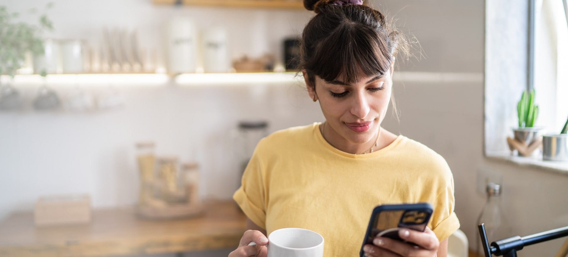 Junge Frau, die fröhlich auf ihr Smartphone schaut.